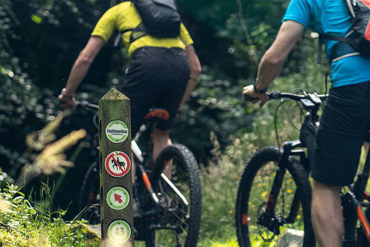 Mountain bike trail markers and two mountain bikers riding past