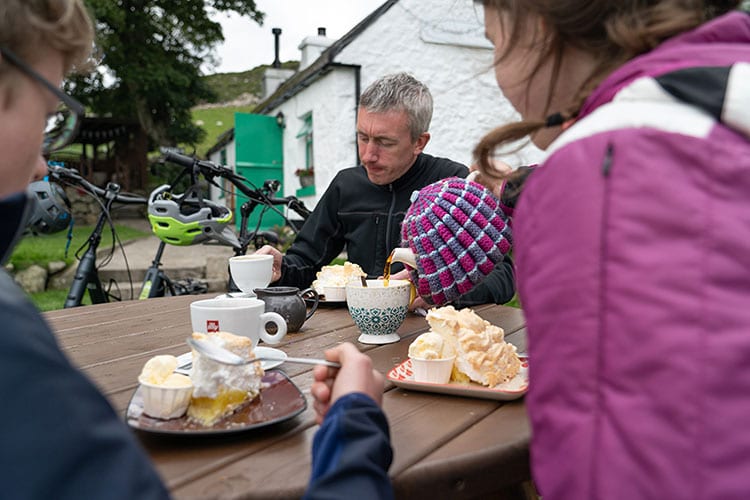 Enjoying dessert at Carrick Cottage Cafe, Mourne Mountains Three mountain bikers drinking tea and eating traybakes at Carrick Cottage, Mourne Mountains