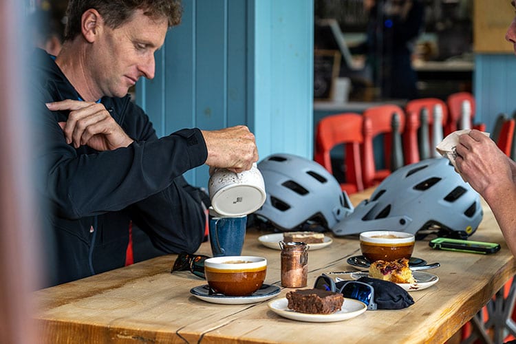 Two mountain bikers enjoying hot drinks and traybake in Synge & Burn at the end of the Rostrevor Red MTB trail